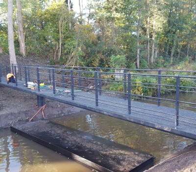 Aanbrengen stalen voetgangersbrug en trapopgangen in wandelgebied